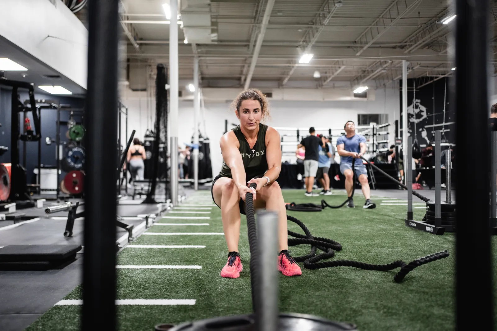 Athlete pulling a weighted sled across the turf in a HYROX class at Hidden Gym Allen